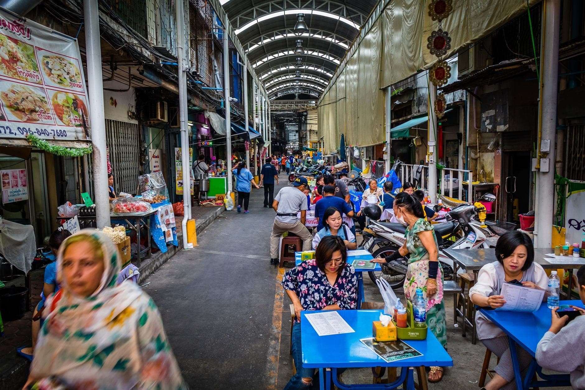 Tętniący życiem targ z ulicznym jedzeniem w Chiang Mai z miejscowymi i turystami jedzącymi przy stolikach na świeżym powietrzu, otoczony straganami i sprzedawcami żywności.