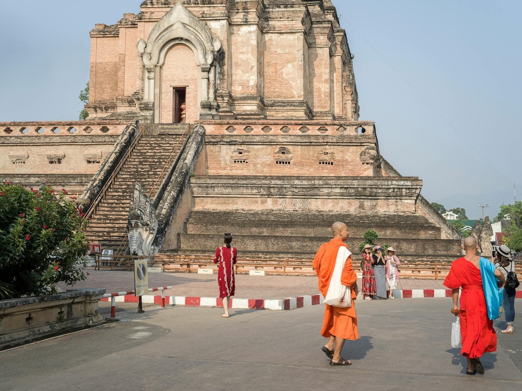 Chiang Mai'deki Wat Chedi Luang tapınağının önünde yürüyen keşişler ve ziyaretçiler, tapınak yaşamını ve geleneksel kıyafetleri gözler önüne seriyor.