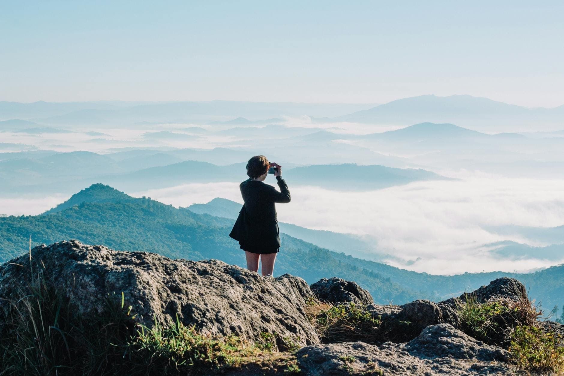 Persona de pie sobre un afloramiento rocoso contemplando un paisaje montañoso brumoso en la ruta de Chiang Mai a Pai