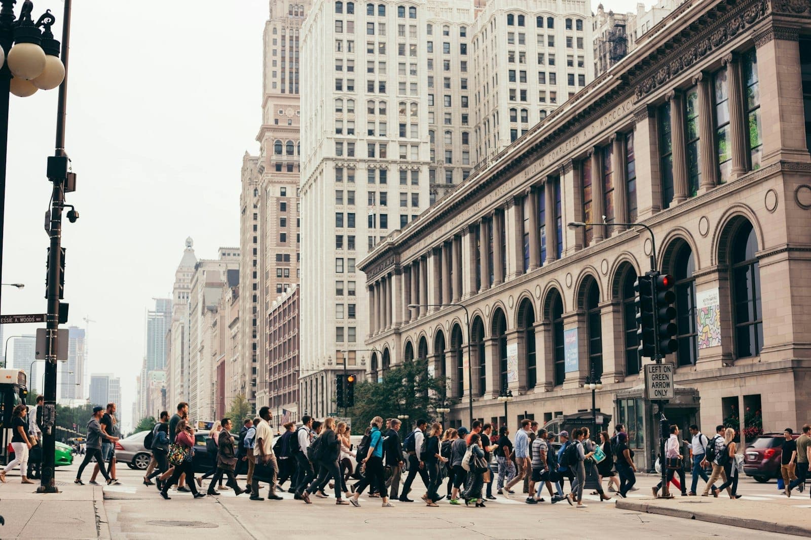 Crowds of people crossing a busy intersection on North Michigan Avenue, surrounded by historic and modern skyscrapers in downtown Chicago.