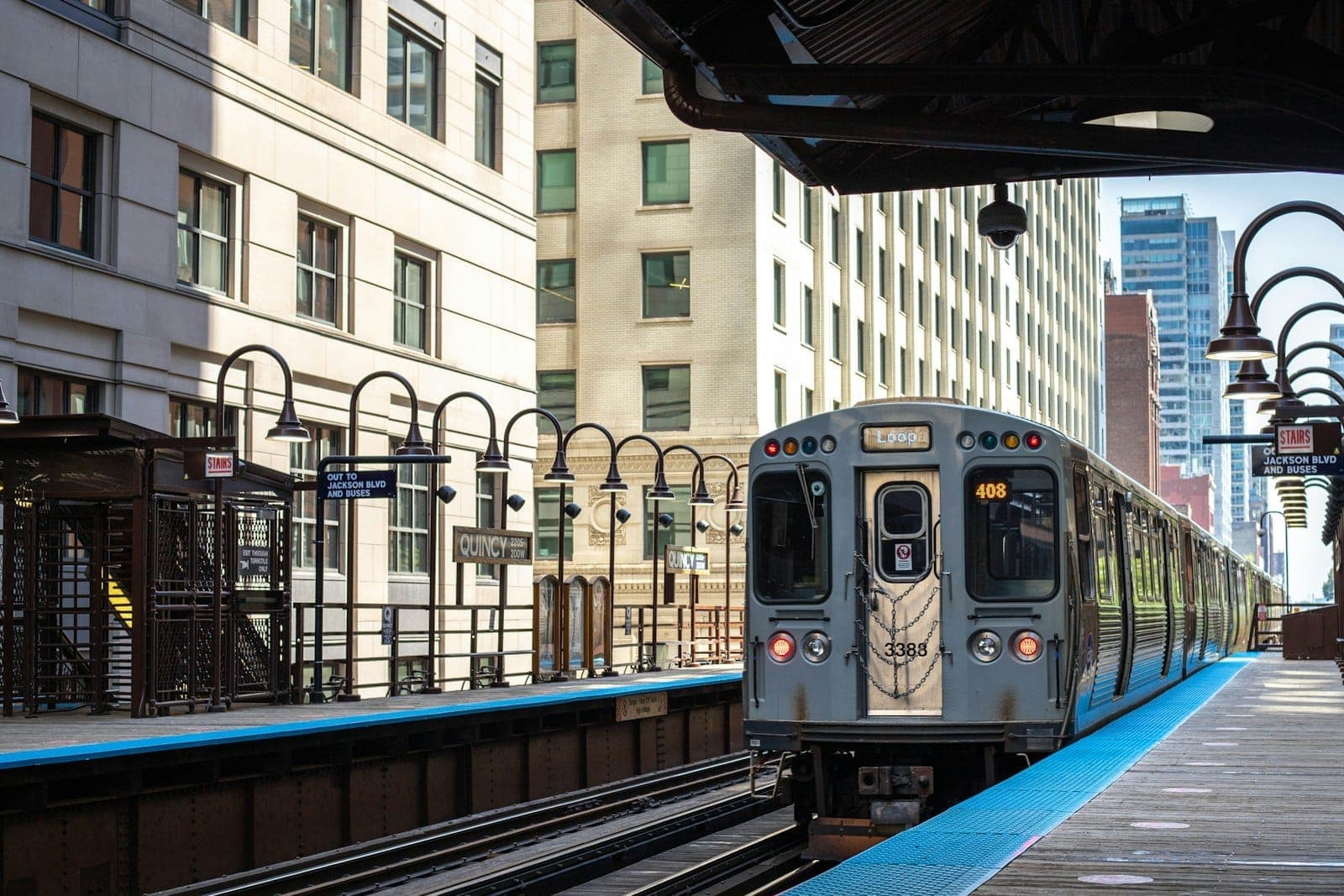 Chicagos 'L'-Bahn fährt an einem klaren Tag in eine erhöhte Bahnsteig im Stadtzentrum ein, umgeben von hohen Gebäuden.