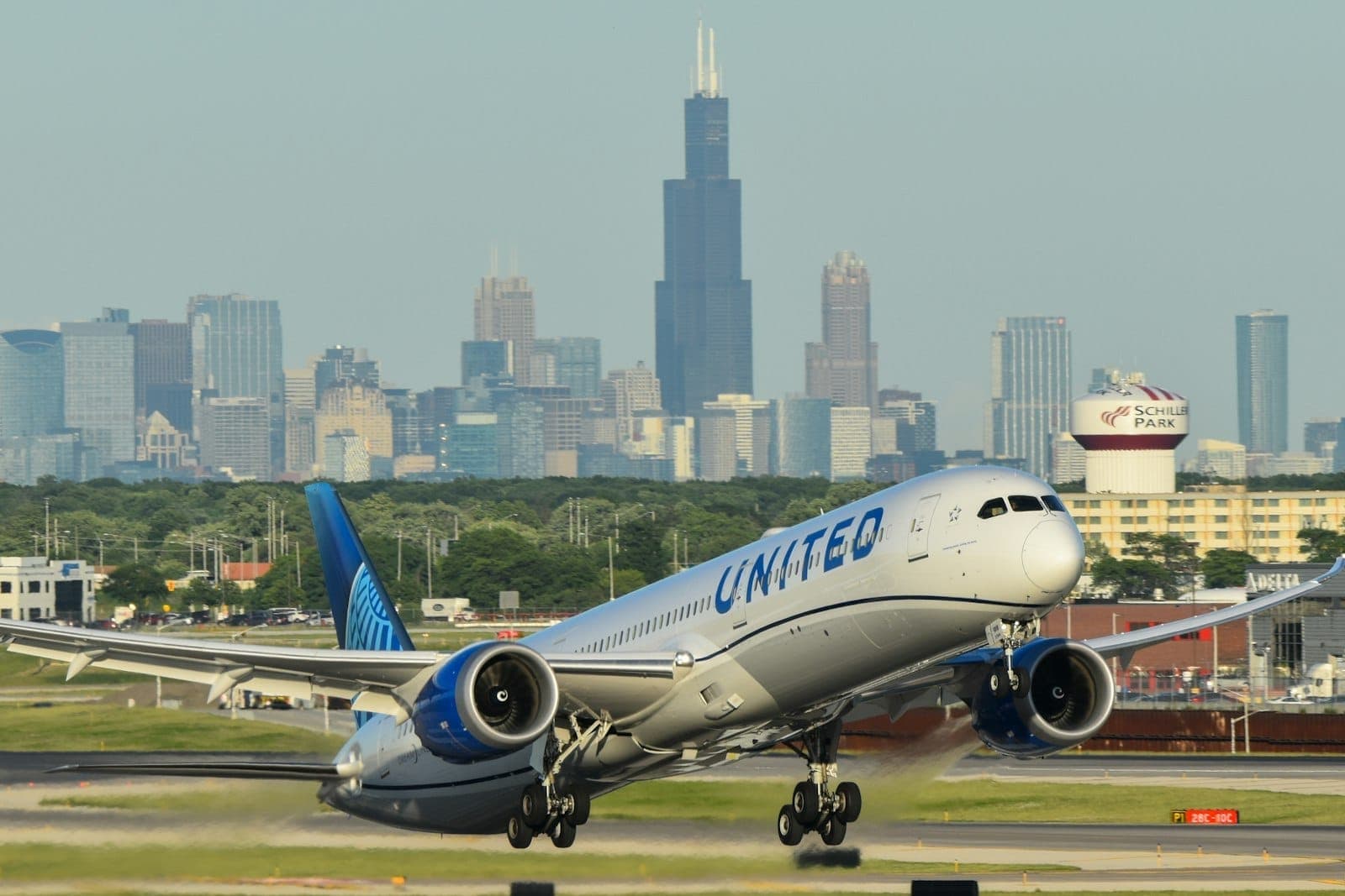 Ein United-Flugzeug hebt am Chicagoer Flughafen ab, im Hintergrund ist die Skyline Chicagos mit dem Willis Tower an einem klaren Tag zu sehen.
