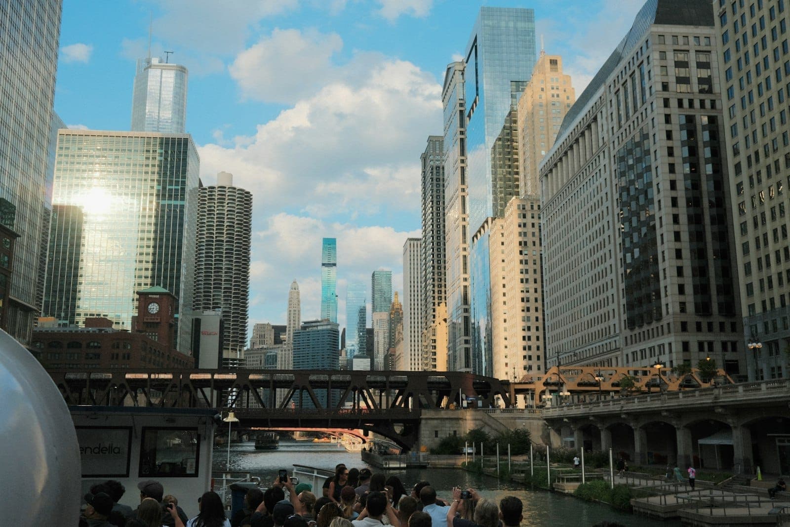 Barco turístico lleno de personas navegando por el Chicago River, rodeado de los icónicos rascacielos del centro en un día soleado.