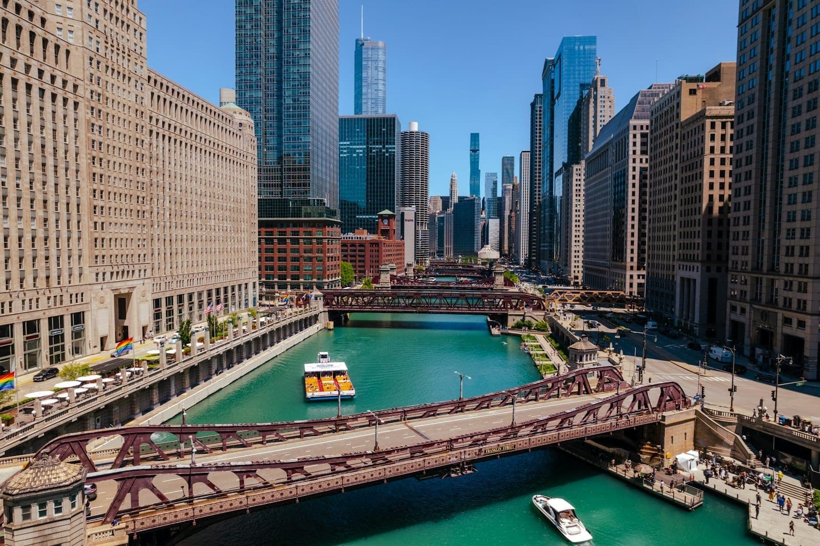 Una vibrante vista de barcos navegando por el río Chicago rodeados de rascacielos y la icónica arquitectura del centro en un día soleado.