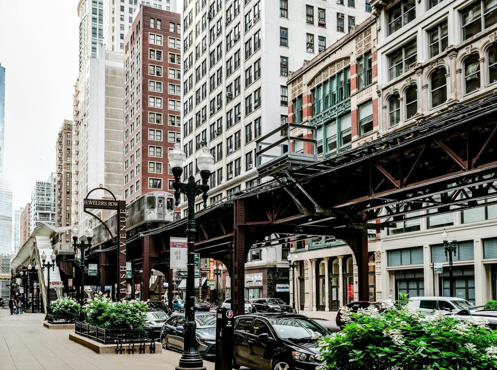 Chicago city street scene with elevated train tracks, historic buildings, and parked cars in the downtown restaurant district.