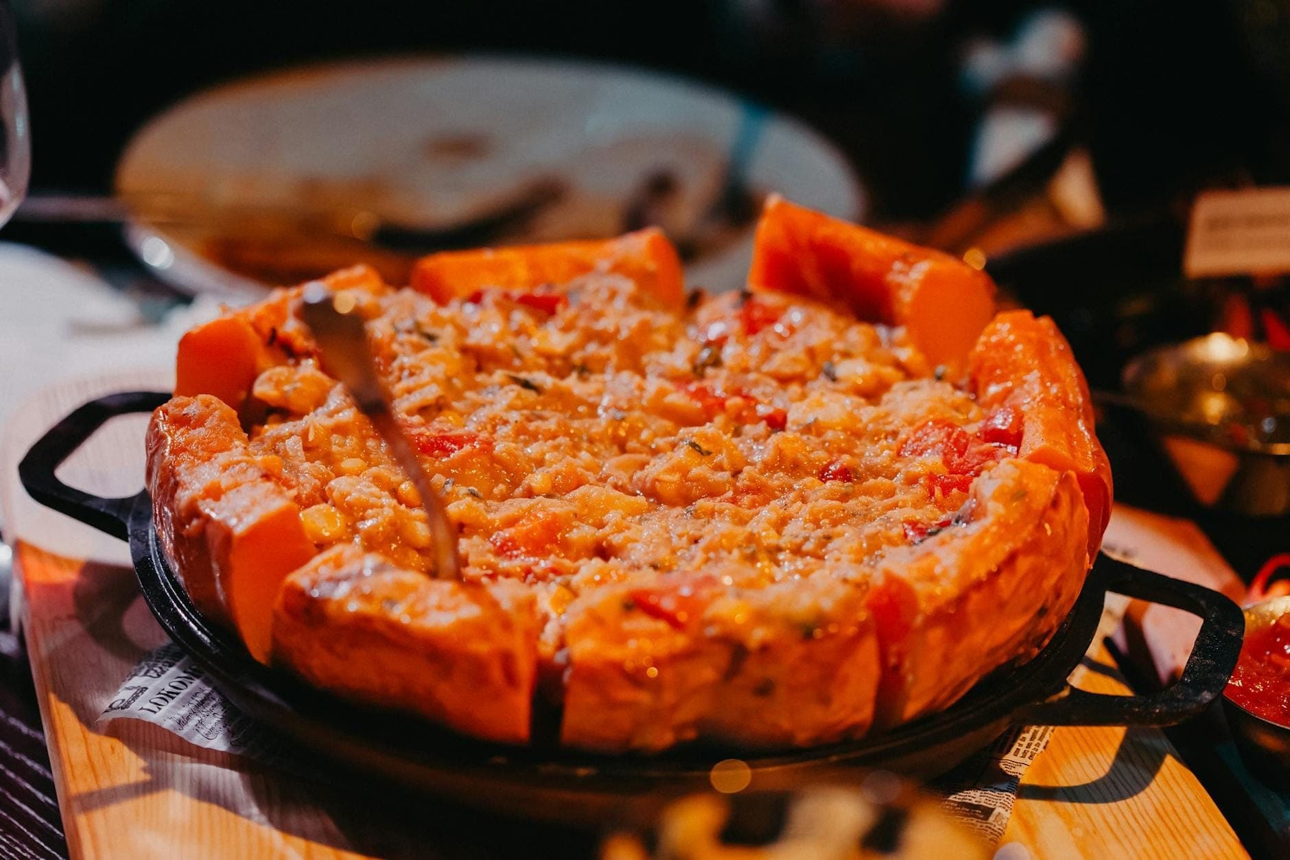 A fresh Chicago deep-dish pizza with golden crust and cheesy topping sits on a cast iron pan in a cozy restaurant setting.
