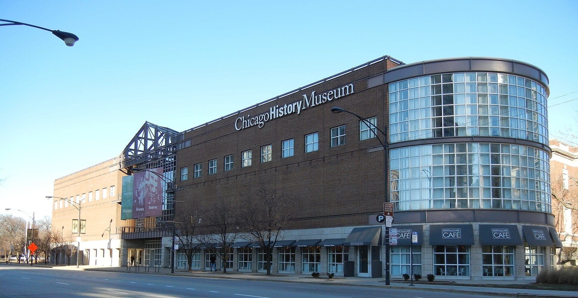 วิวถนนของอาคาร Chicago History Museum พร้อมด้านหน้าอาคารกระจกสมัยใหม่ ผนังอิฐ และป้ายที่ชัดเจนในวันที่อากาศแจ่มใส