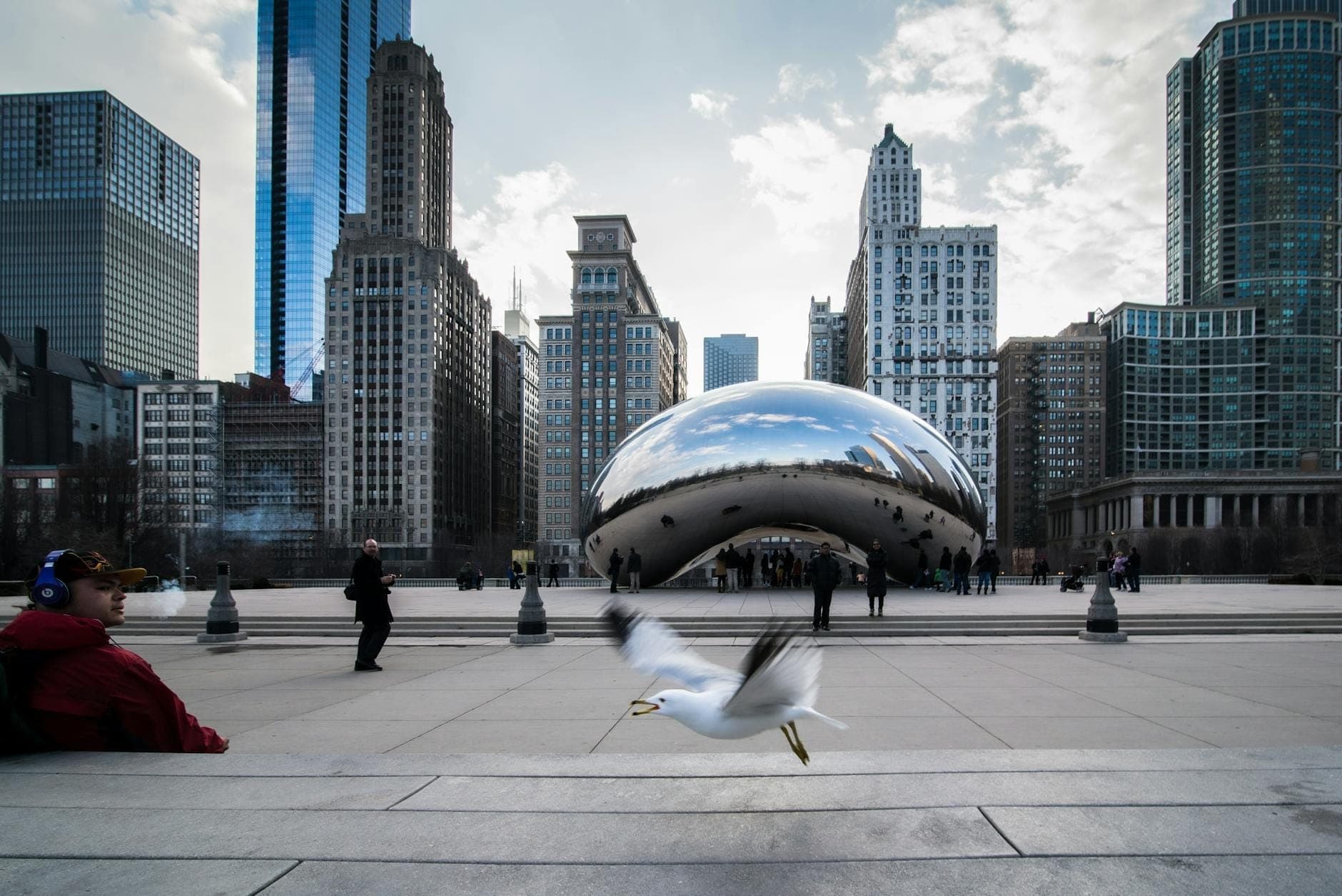 Cloud Gate sculpture with people and Chicago skyscrapers in the background on a winter day.