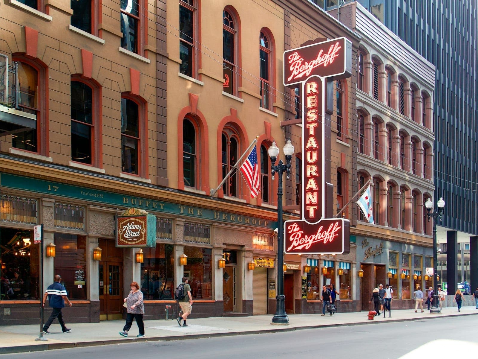 Cảnh đường phố của Berghoff Restaurant ở trung tâm thành phố Chicago, với người đi bộ và các lá cờ Chicago được trưng bày.