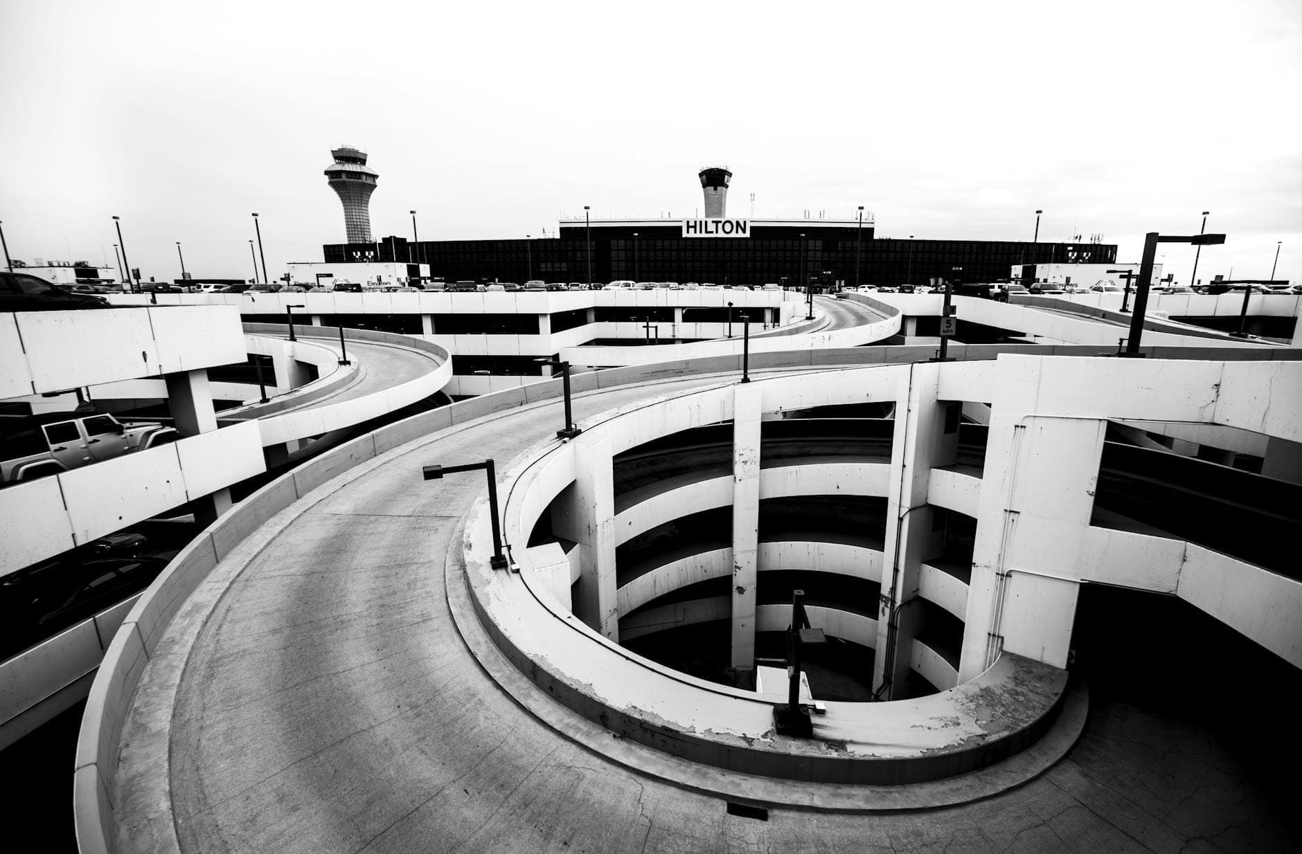 Black and white view of O'Hare International Airport with curving parking structure and control towers visible.