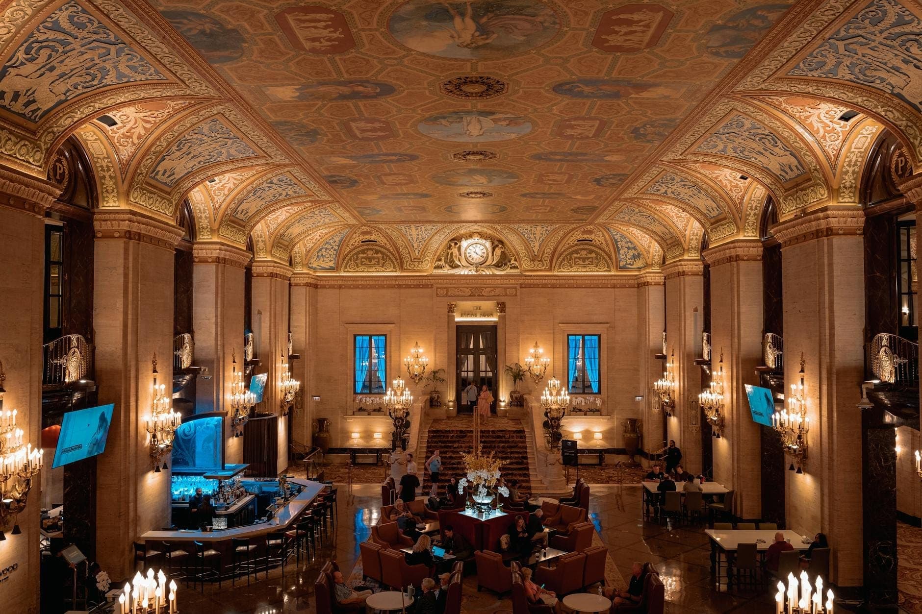 Grand lobby of a luxury hotel in Chicago with ornate painted ceilings, elegant chandeliers, and refined guests relaxing in plush seating.