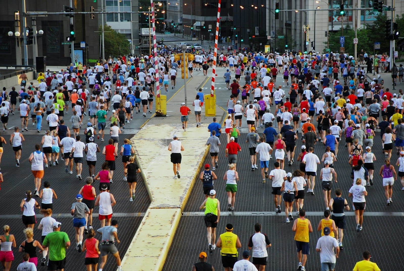 A large group of runners participating in a marathon crosses a city bridge with downtown Chicago buildings in the background.