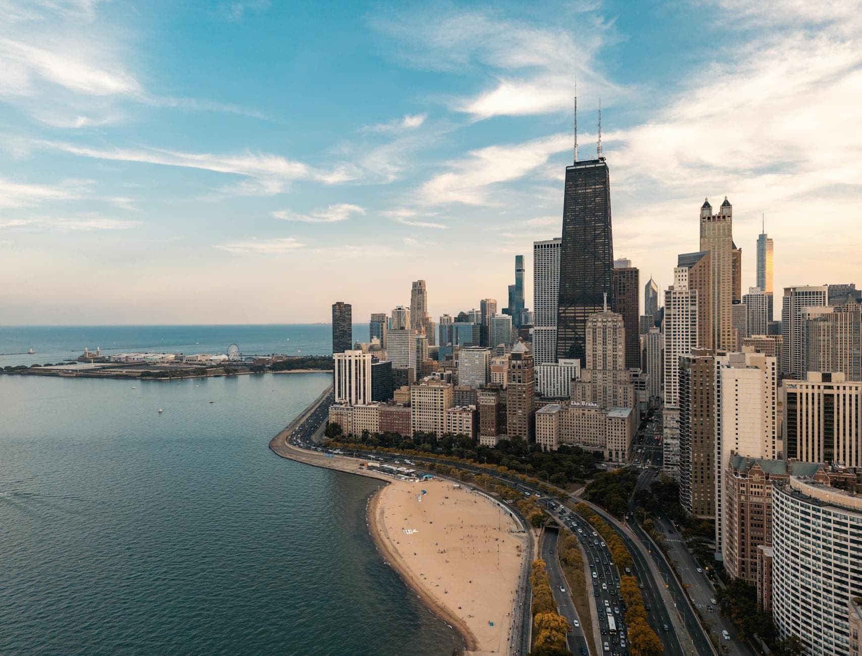 Lakefront view of Chicago skyline with sandy beach and clear skies, suggesting pleasant off-peak travel weather.