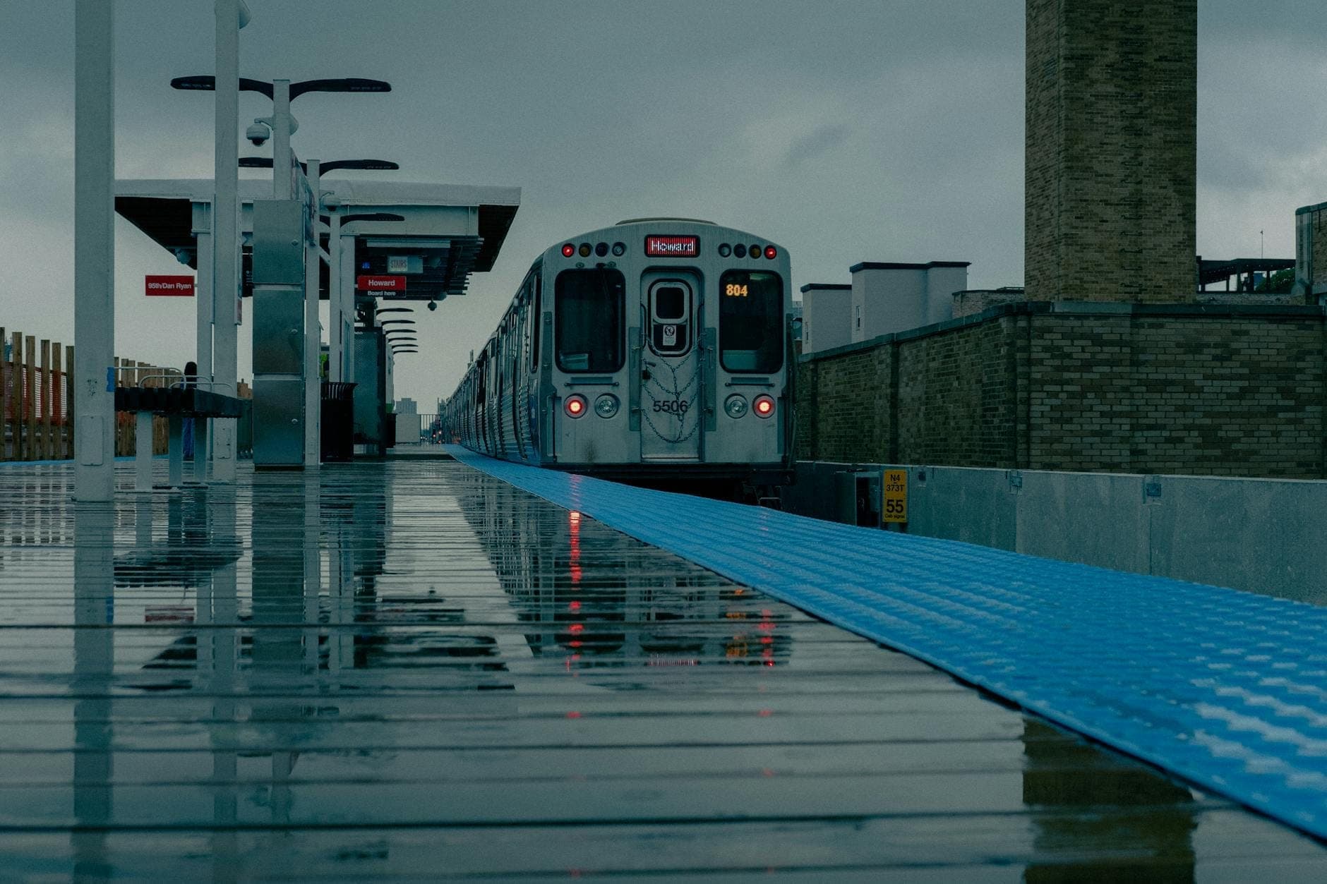 Chicago CTA Blue Line train at a modern station platform with wet ground and blue tactile edging, matching the section’s safety context.