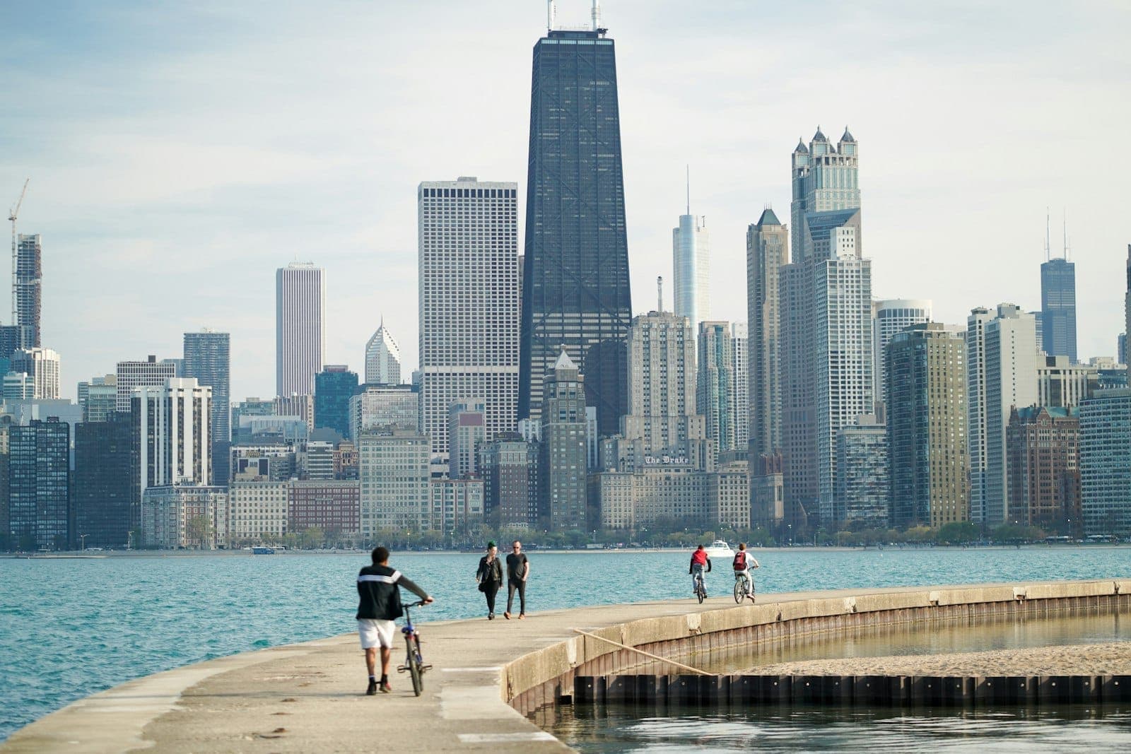 People biking and walking on a lakeshore path in front of the Chicago skyline on a bright day, evoking safety and vibrancy for tourists.