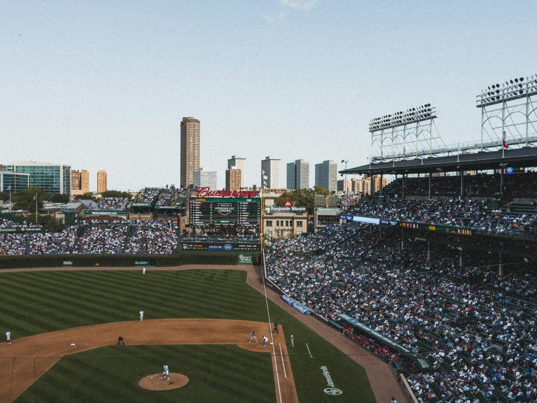 Wide view of a crowded baseball stadium in Chicago with the city skyline in the background on a clear day.