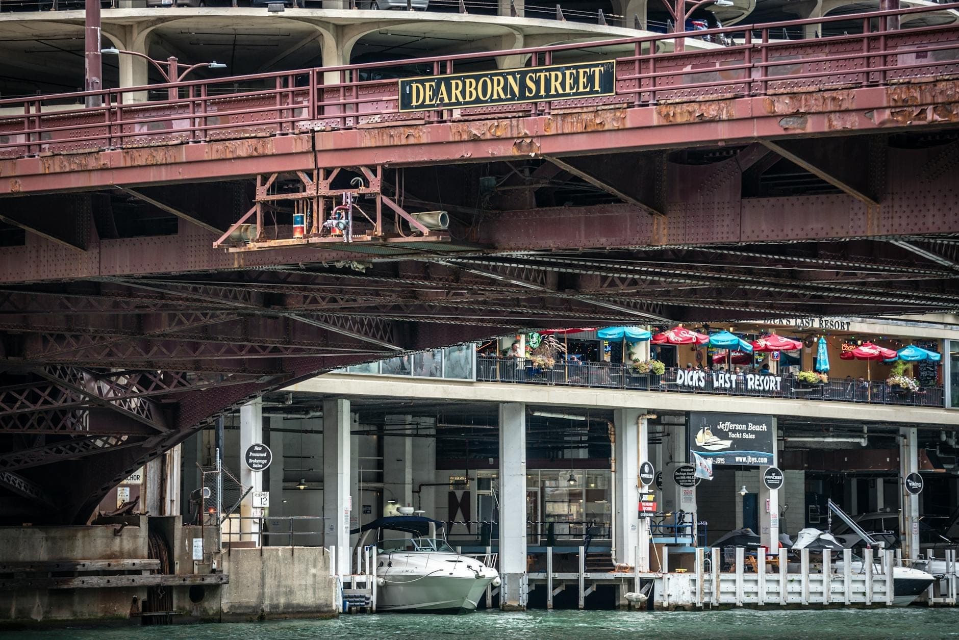 View of the Dearborn Street bridge in Chicago with outdoor restaurant seating visible by the riverfront.