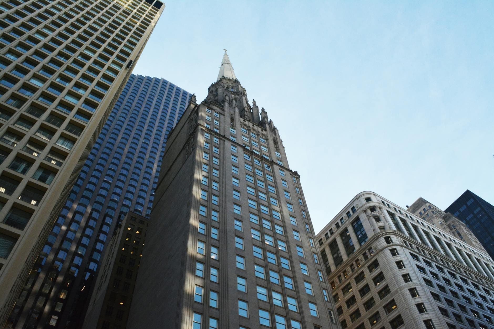 Chicago Temple Building with its distinctive Gothic spire rising above a downtown skyscraper, surrounded by other tall buildings in the city’s Loop district.