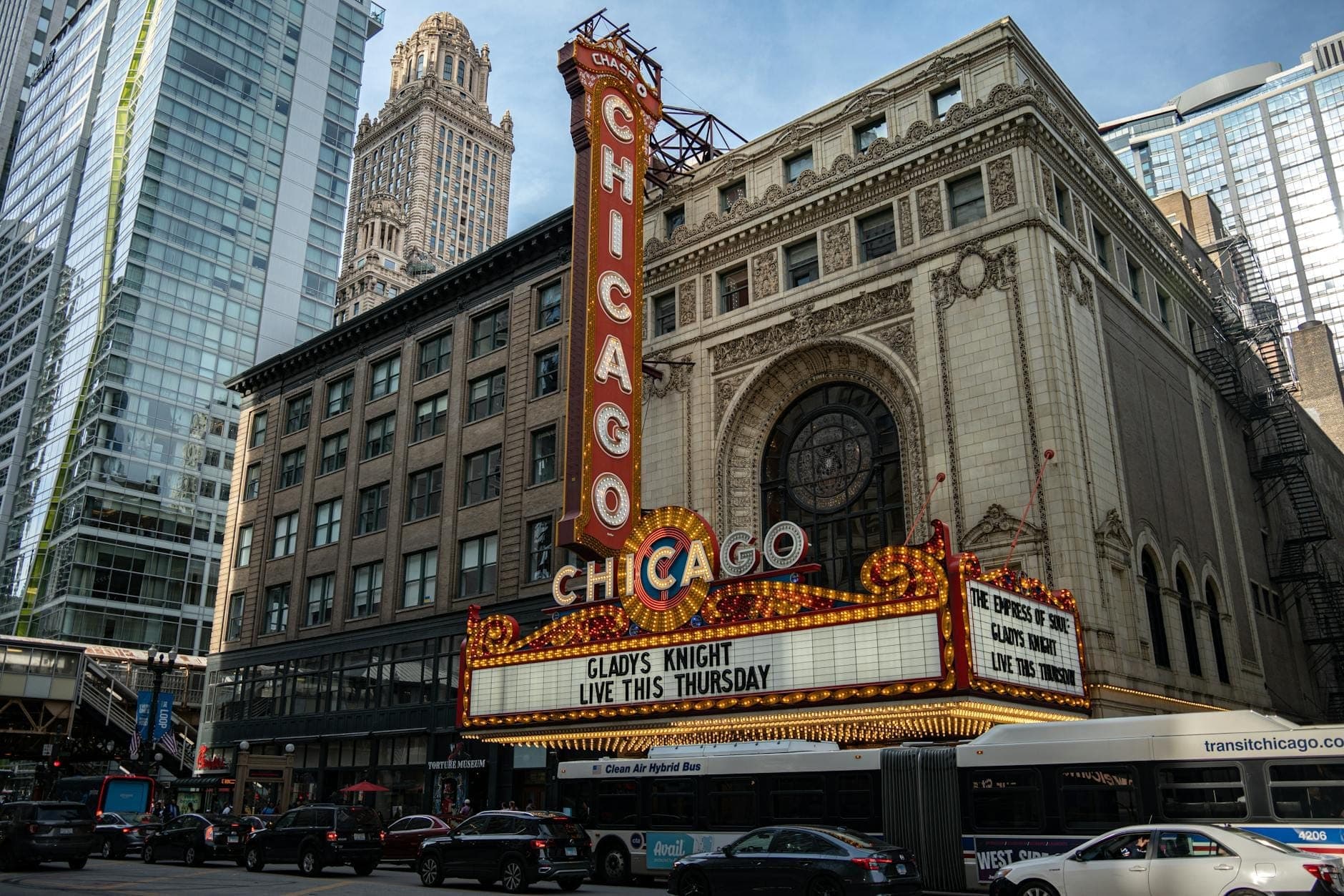 Straßenansicht des ikonischen Chicago Theatre mit seinem hell erleuchteten Marquee-Schild, umgeben von Stadtgebäuden und Verkehr am Tag.