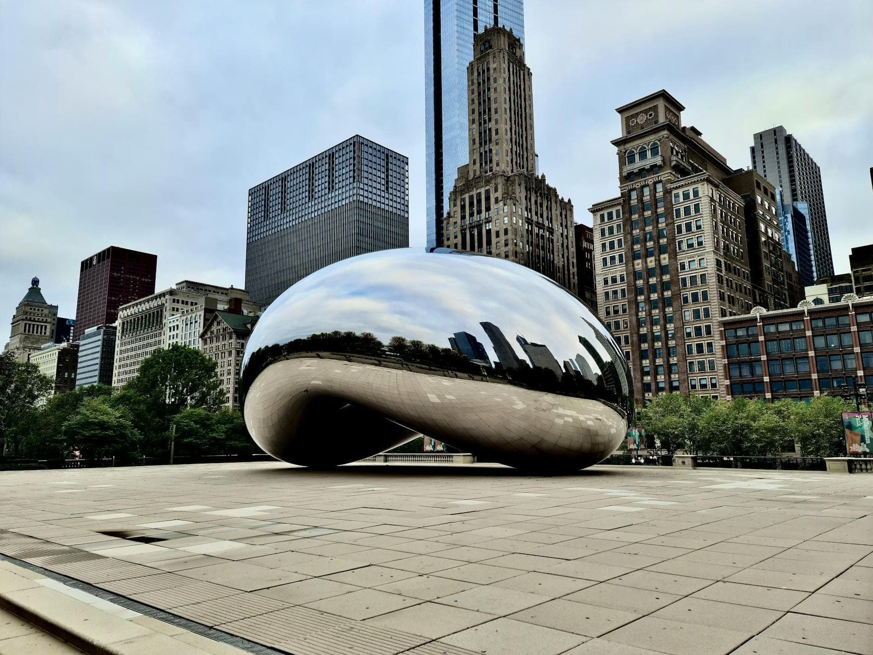 The Cloud Gate sculpture, known as 'The Bean,' with Chicago skyscrapers behind it in Millennium Park on a mostly empty morning.