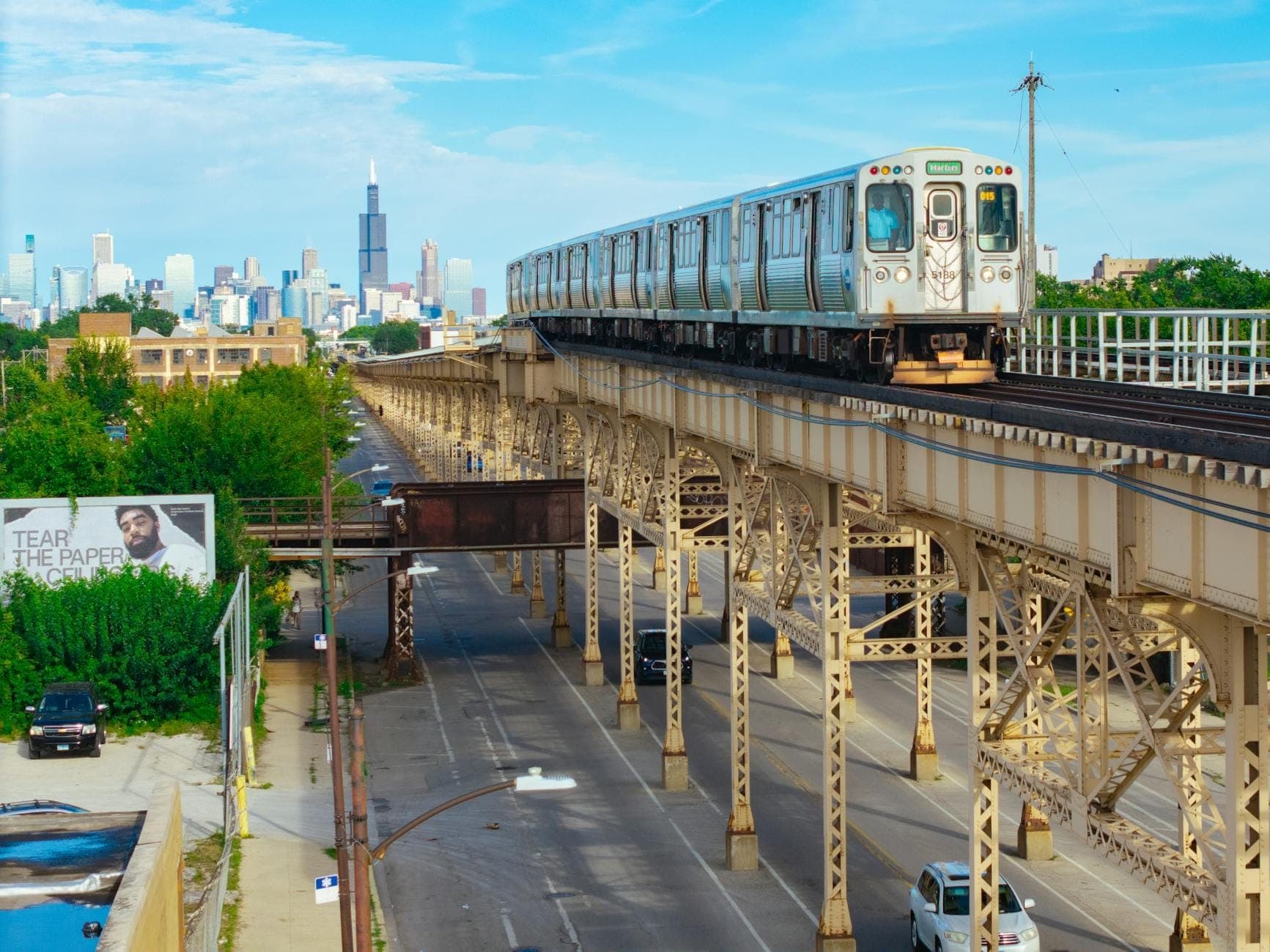 Chicago CTA L-Bahn auf Hochgleisen mit der Skyline der Stadt und dem Willis Tower im Hintergrund an einem sonnigen Tag.
