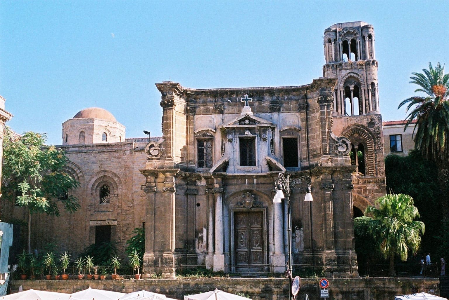 Fasad Gereja Martorana di Palermo, menampilkan elemen arsitektur Norman dan Bizantium, jendela melengkung, dan menara lonceng yang khas di bawah langit cerah.