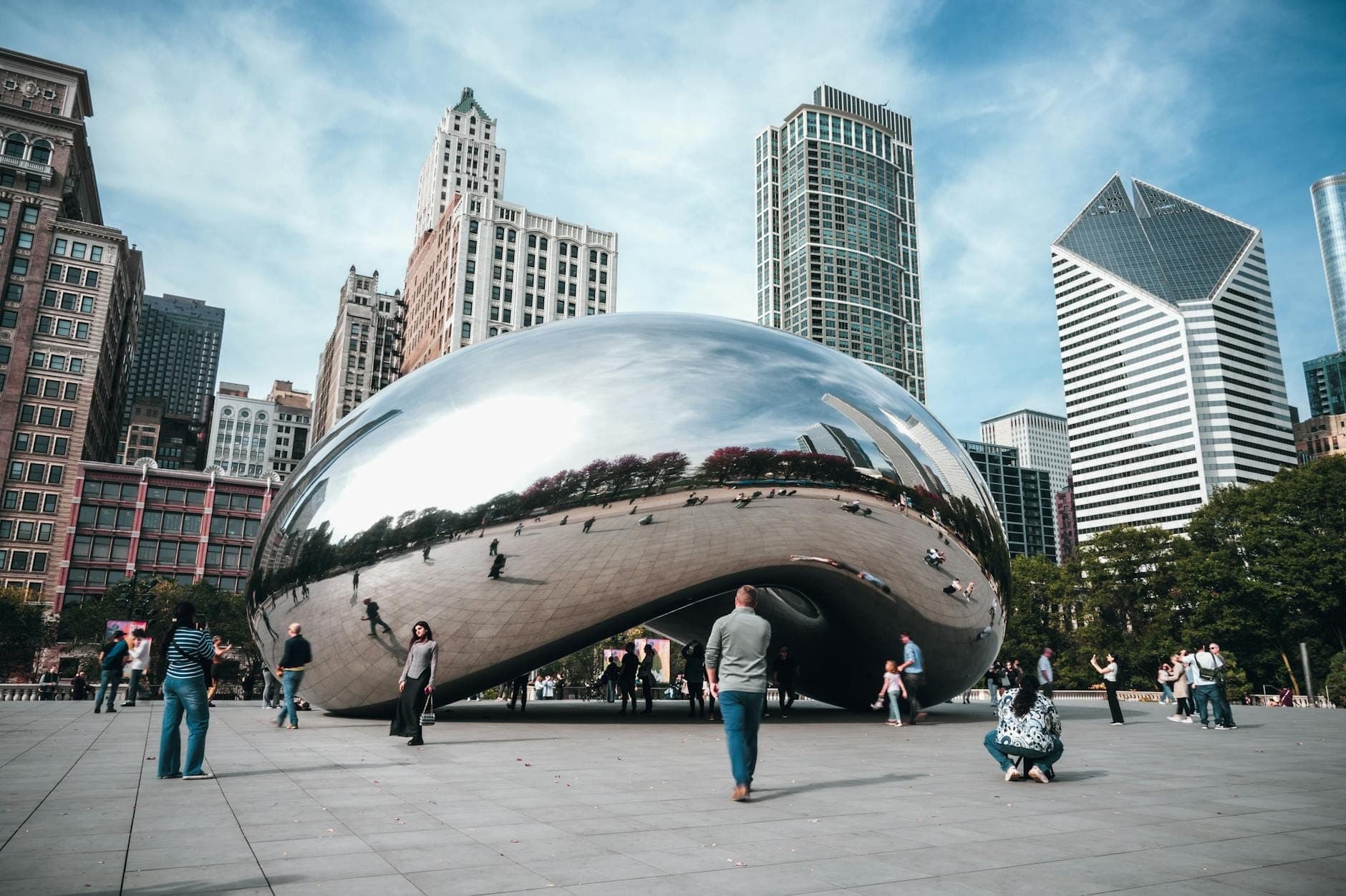 Cloud Gate, also known as The Bean, reflects Chicago’s skyline and visiting tourists under a blue sky in Millennium Park.