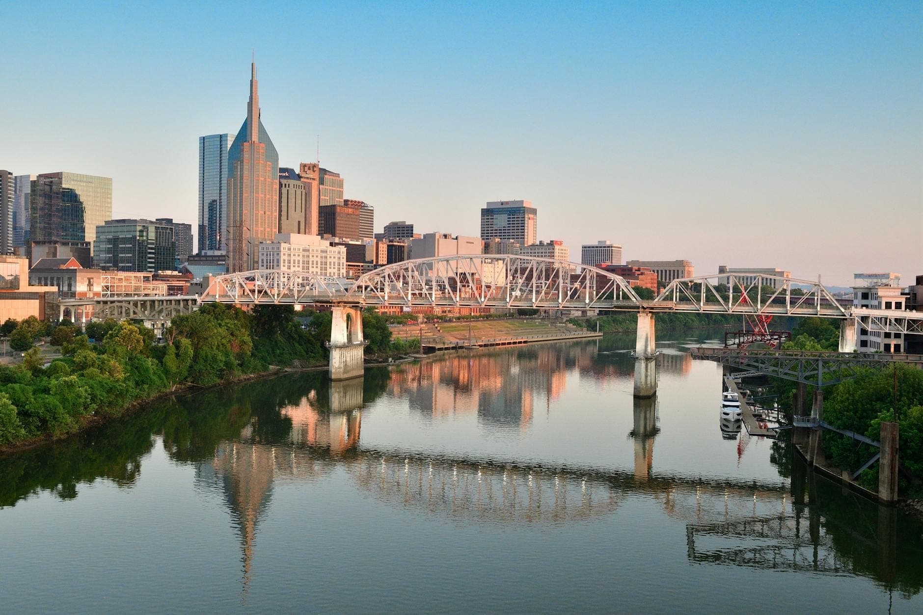 Skyline der Innenstadt von Nashville mit dem ikonischen AT&T-Gebäude und einer Brücke über den Fluss an einem klaren Tag.