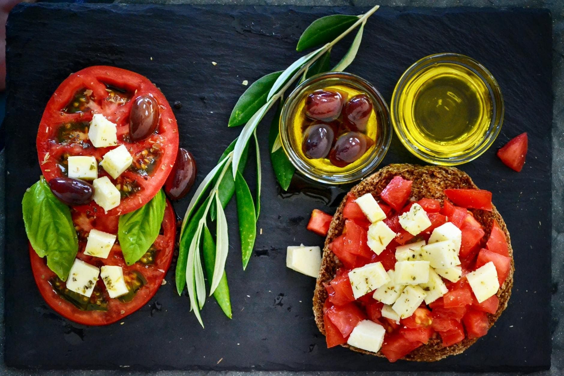 Teller mit Dakos mit gewürfelten Tomaten, Käse, Oliven, Olivenöl und frischen Kräutern – ein klassisches kretisches Gericht.