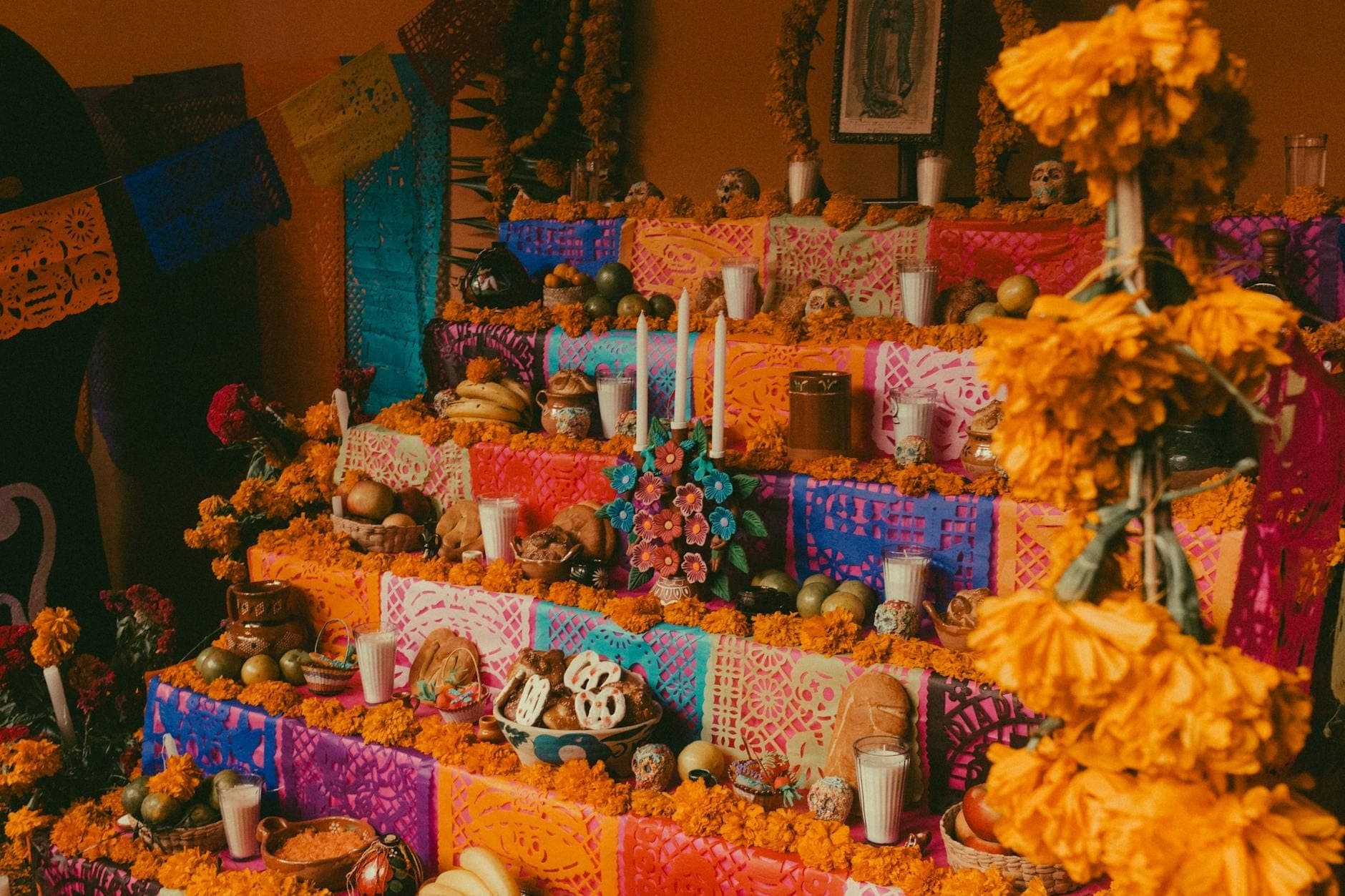 Autel traditionnel à plusieurs niveaux du Día de Muertos avec bougies, soucis, nourriture, crânes en sucre et papel picado coloré à Mexico.