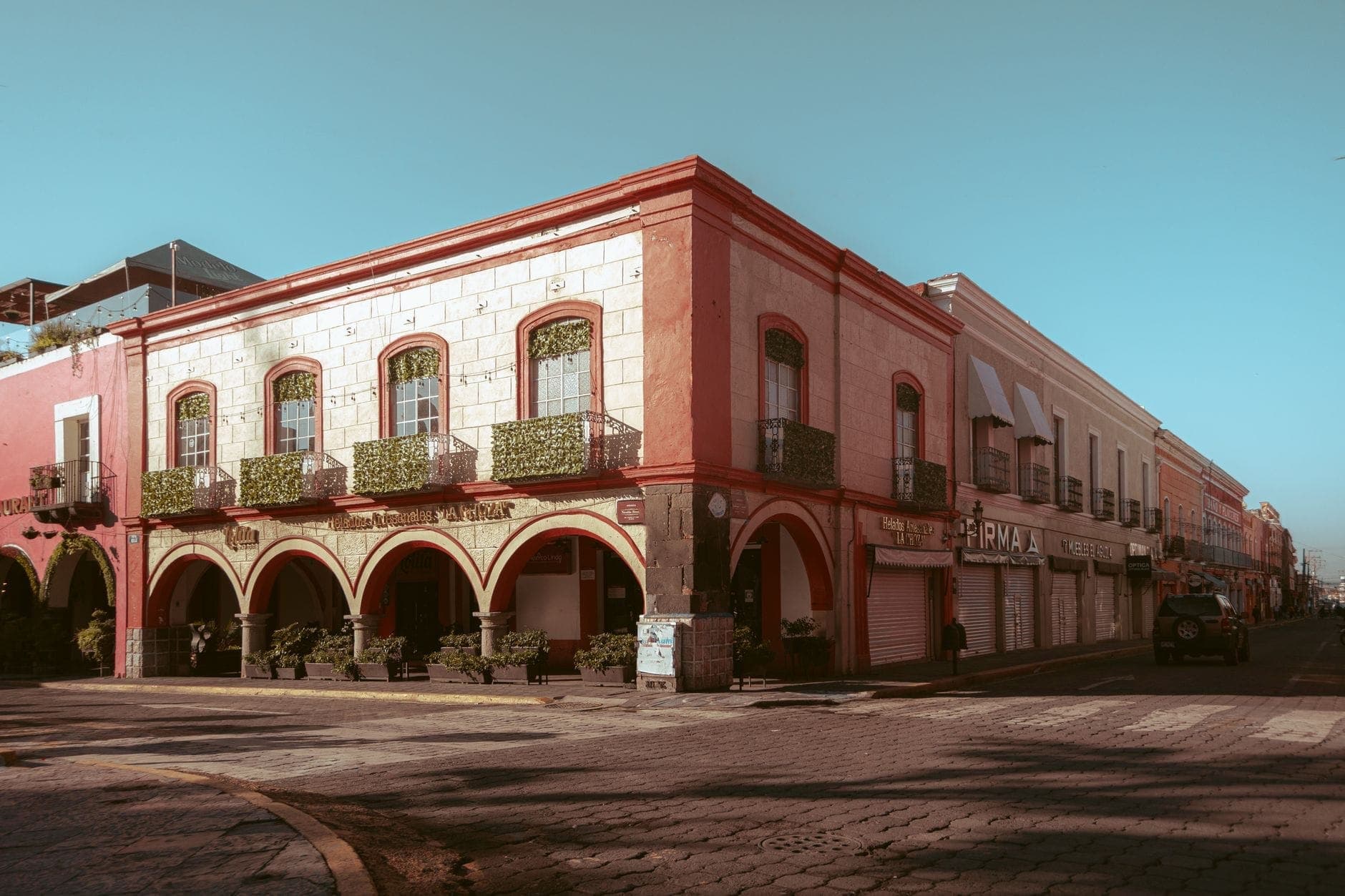 Edificio de la época colonial con arcos y balcones en una esquina soleada, típico de la arquitectura de los pueblos mexicanos.