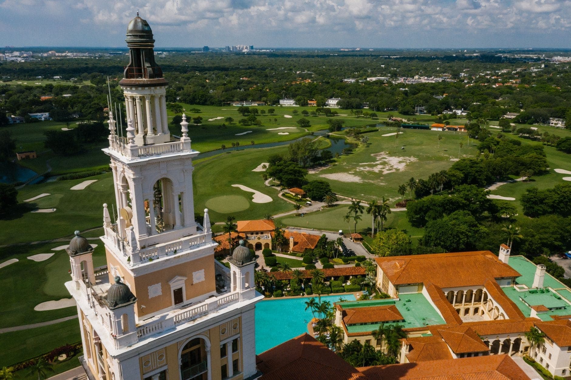 Вид с воздуха на легендарный Biltmore Hotel в Coral Gables с архитектурой средиземноморского возрождения, полем для гольфа и окружающей зеленью.