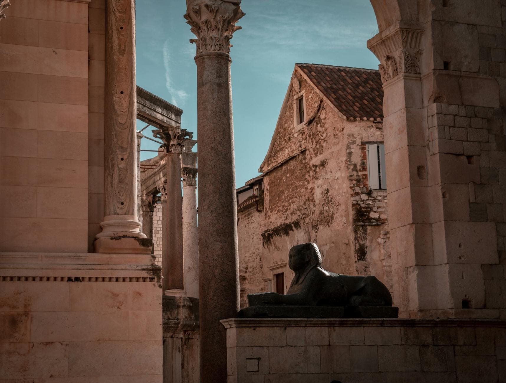 Antiche colonne di pietra, archi e una sfinge di granito nero tra le storiche rovine del Palazzo di Diocleziano a Spalato, in Croazia.