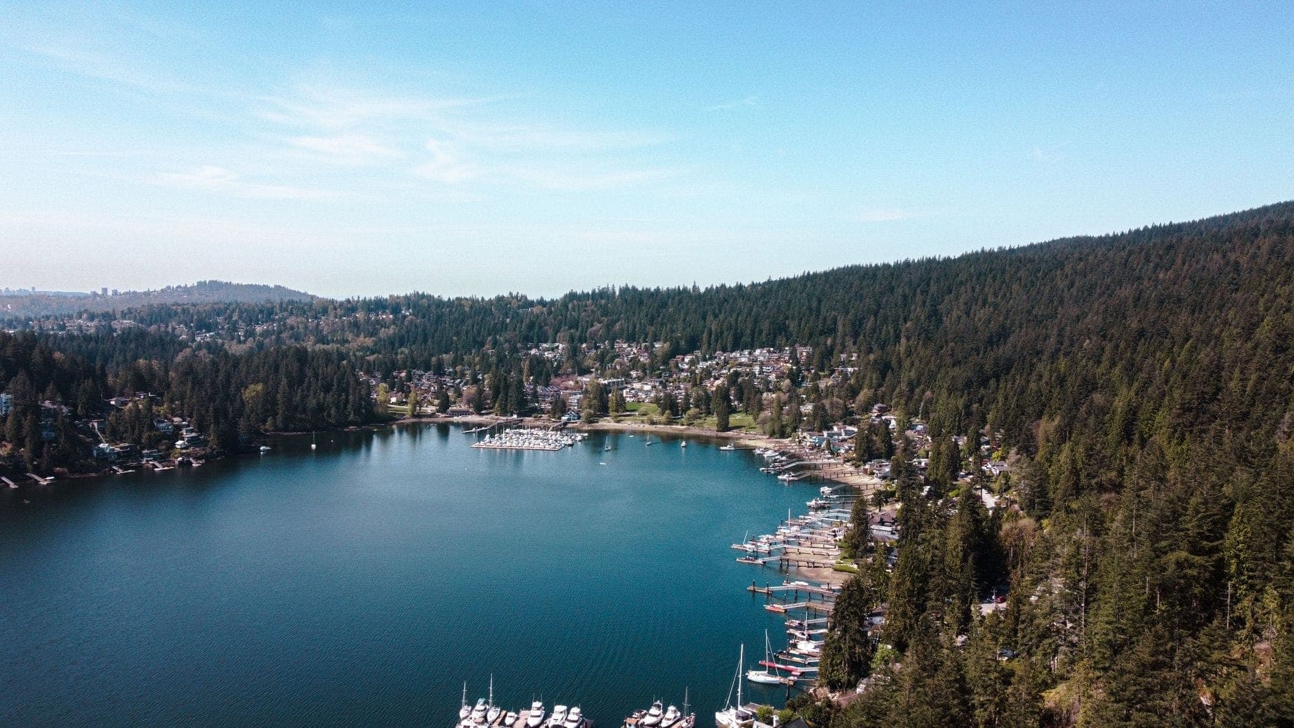 มุมสูงของ Deep Cove เห็นอ่าวน้ำฟ้าสงบ ล้อมด้วยเนินป่าสีเขียว ท่าจอดเรือ และหมู่บ้านเล็กๆ ริมน้ำ