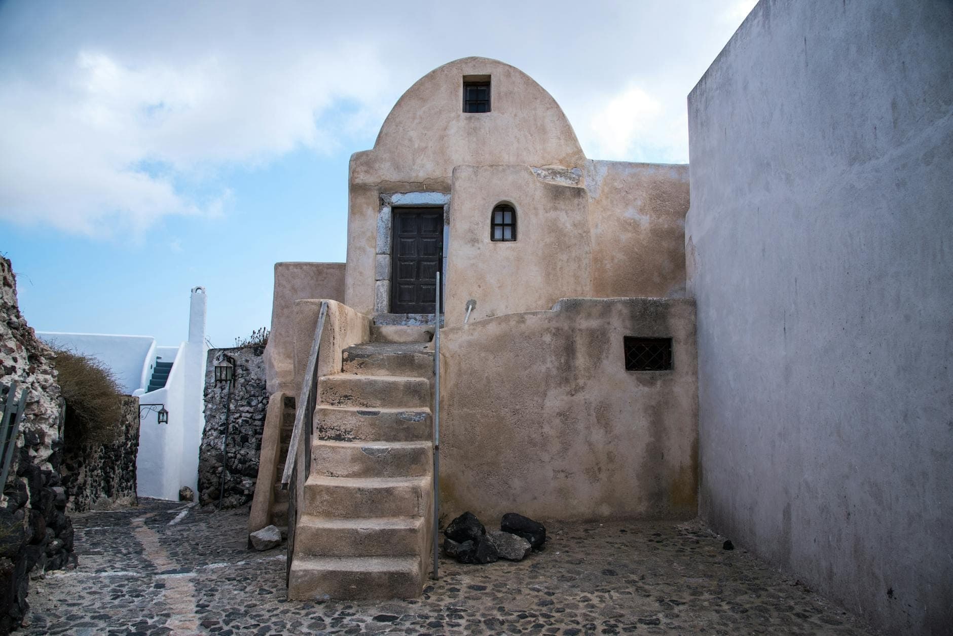 Mittelalterliches Steingebäude mit gewölbtem Dach, alten Stufen und engen Kopfsteinpflastergassen in Emporio, Santorinis besterhaltenes Festungsdorf.