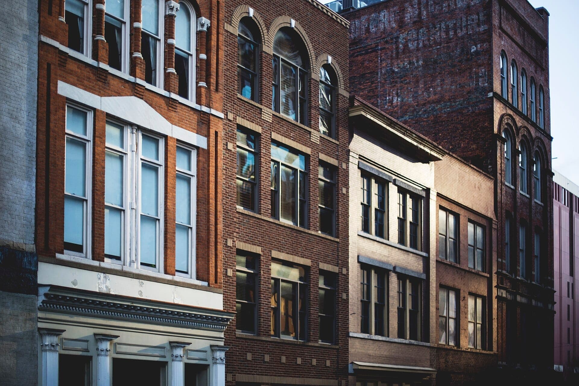 Rows of historic brick buildings with tall windows and ornate details in the Five Points neighborhood of East Nashville, captured in afternoon light.