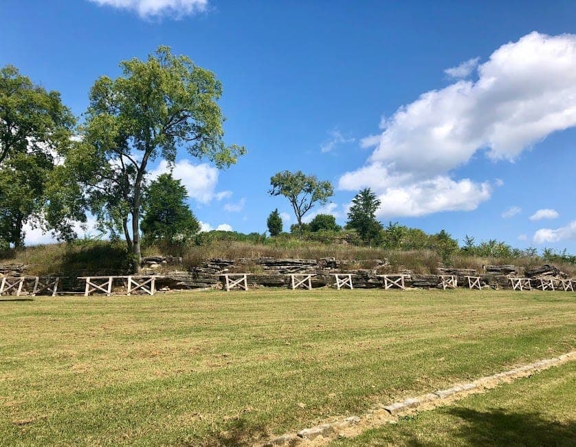 Wide view of Fort Negley Park’s historic stone walls and grassy field under a bright blue sky with scattered clouds and green trees.
