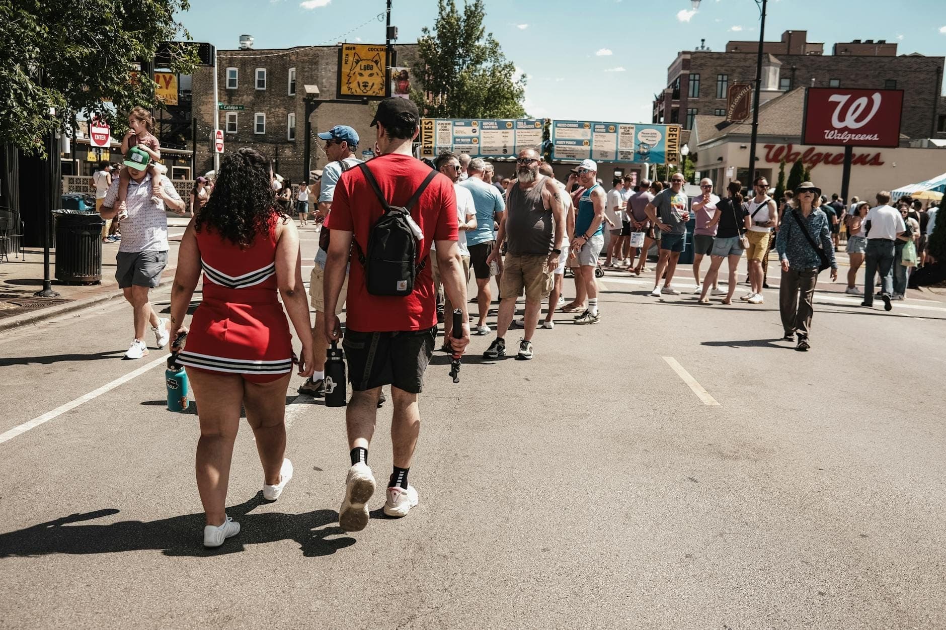 A lively Chicago street festival with crowds walking down a closed street lined with booths and city buildings in the background.