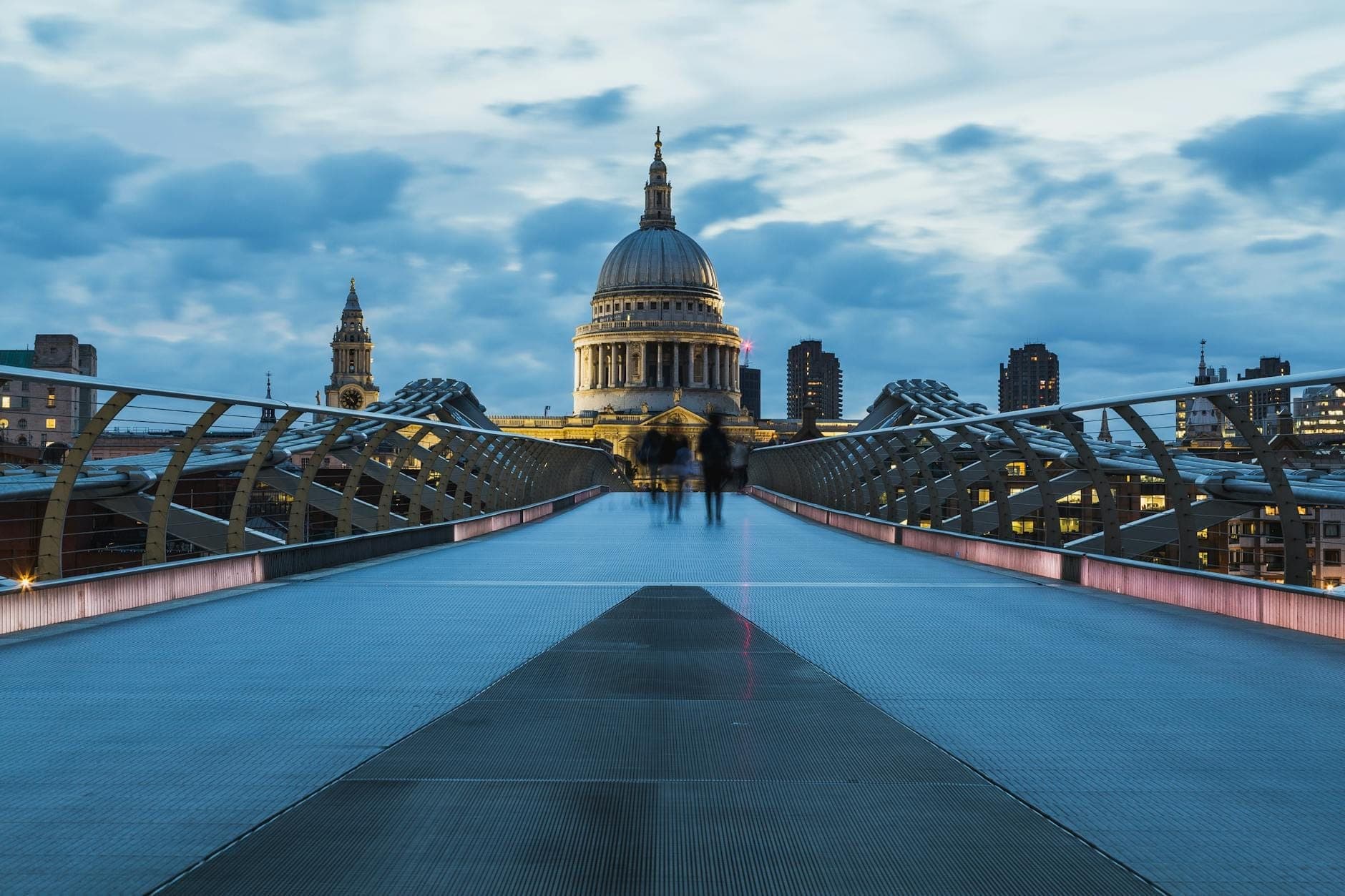 Blick von der Millennium Bridge in Richtung St. Paul's Cathedral in der Abenddämmerung, mit dramatischem Himmel und der Londoner Skyline im Hintergrund.