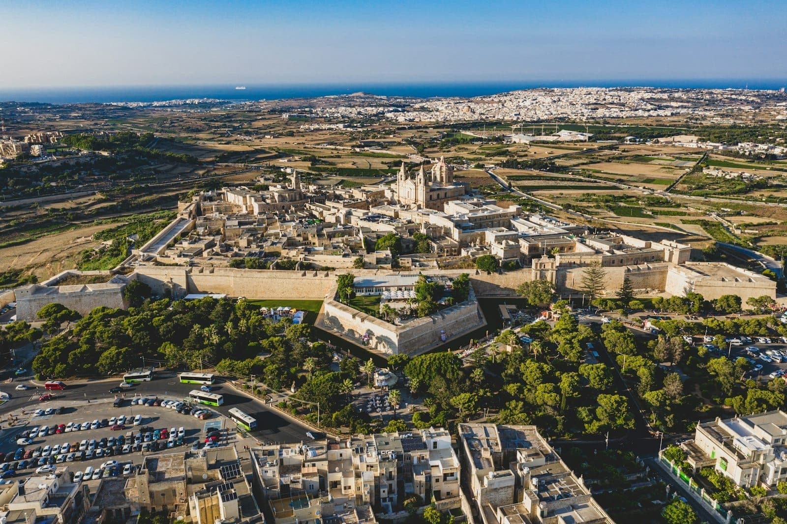 Luftaufnahme der alten Mauerstadt Maltas mit Befestigungsanlagen, historischen Gebäuden und weitem Landschaft bis zur Küste.