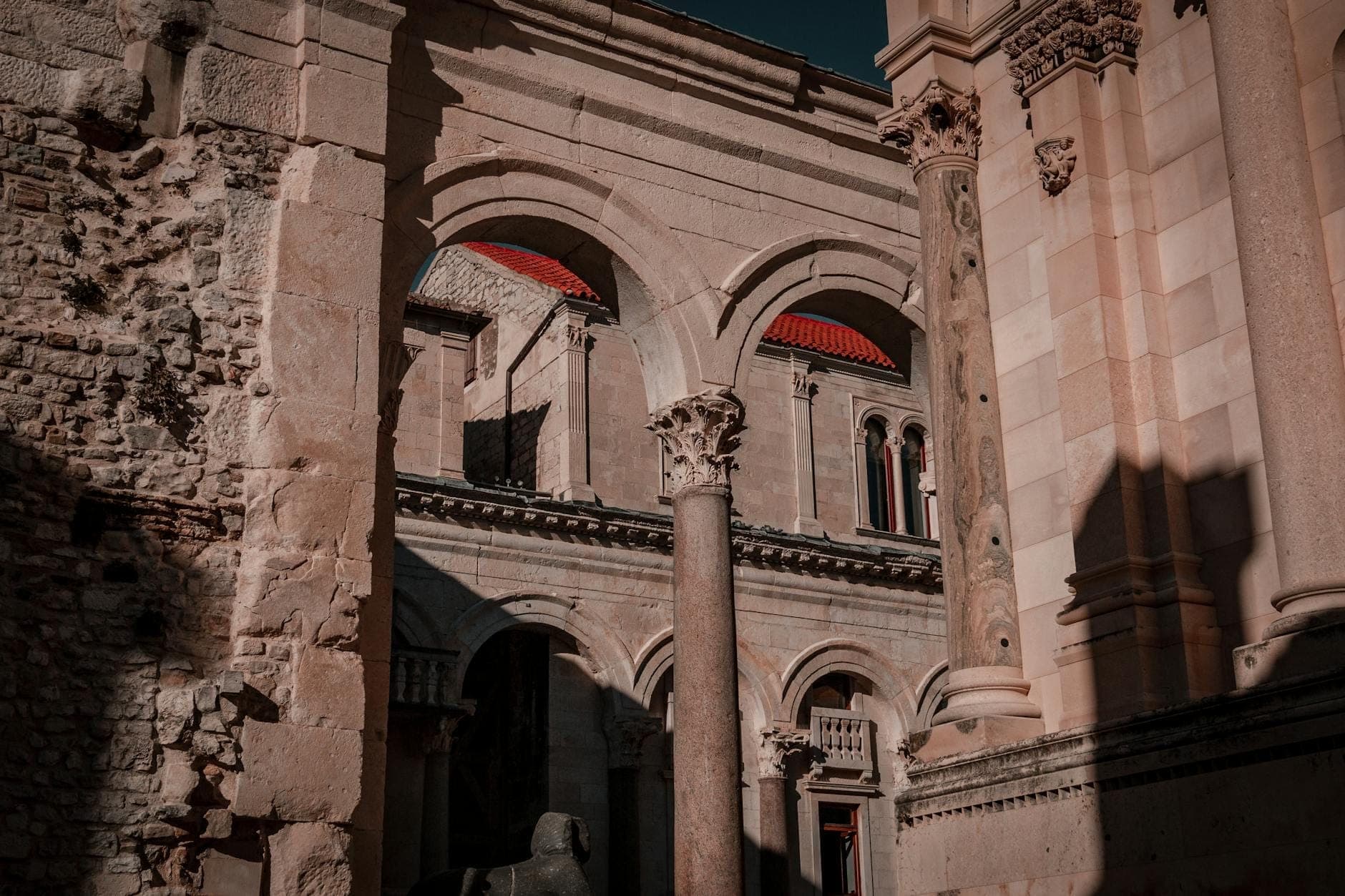 Archi e colonne in pietra del Palazzo di Diocleziano a Spalato, con architettura dettagliata e texture storiche nella calda luce del sole.