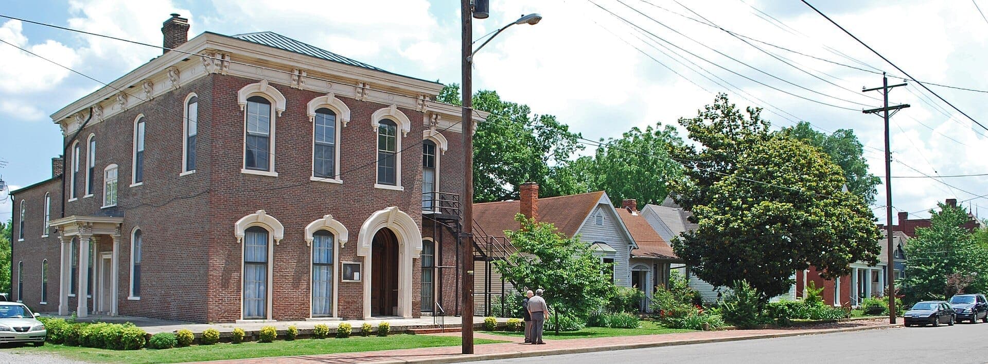 Historic Victorian brick building and charming houses line a quiet street in Germantown, Nashville on a sunny afternoon.