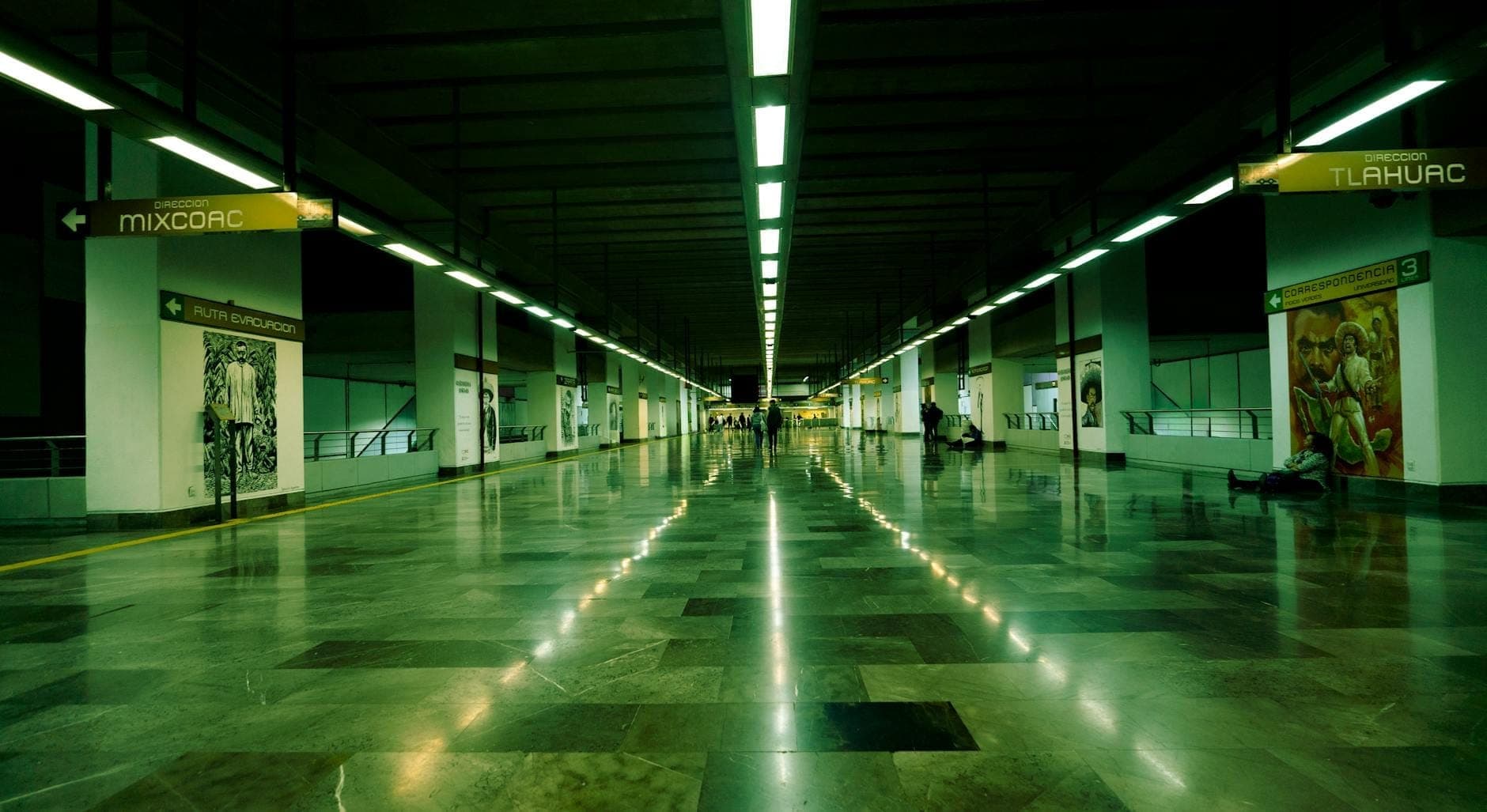 มุมมองกว้างของชานชาลาสถานีรถไฟใต้ดินในเม็กซิโกซิตี้ พร้อมป้ายบอกทางไปยัง Mixcoac และ Tlahuac แสงสว่างทันสมัย และผู้คนบางส่วนกำลังรอขึ้นรถ