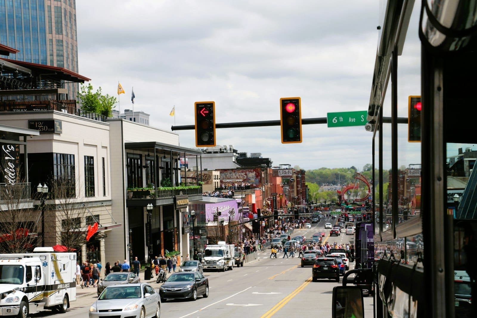 Belebte Straßenszene in Nashville mit Autos, Bussen und Fußgängern unter Ampeln und Stadtgebäuden – ein Überblick über die verschiedenen Transportmöglichkeiten der Stadt.