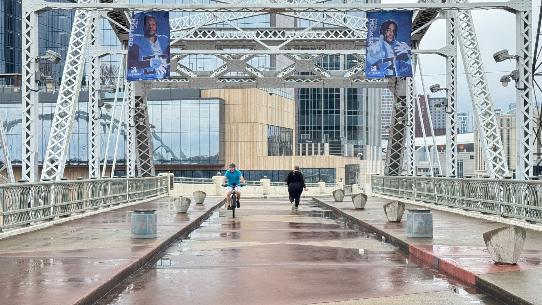Menschen, die auf der John Seigenthaler Pedestrian Bridge in Nashville spazieren und Fahrrad fahren, mit den Gebäuden der Innenstadt im Hintergrund.