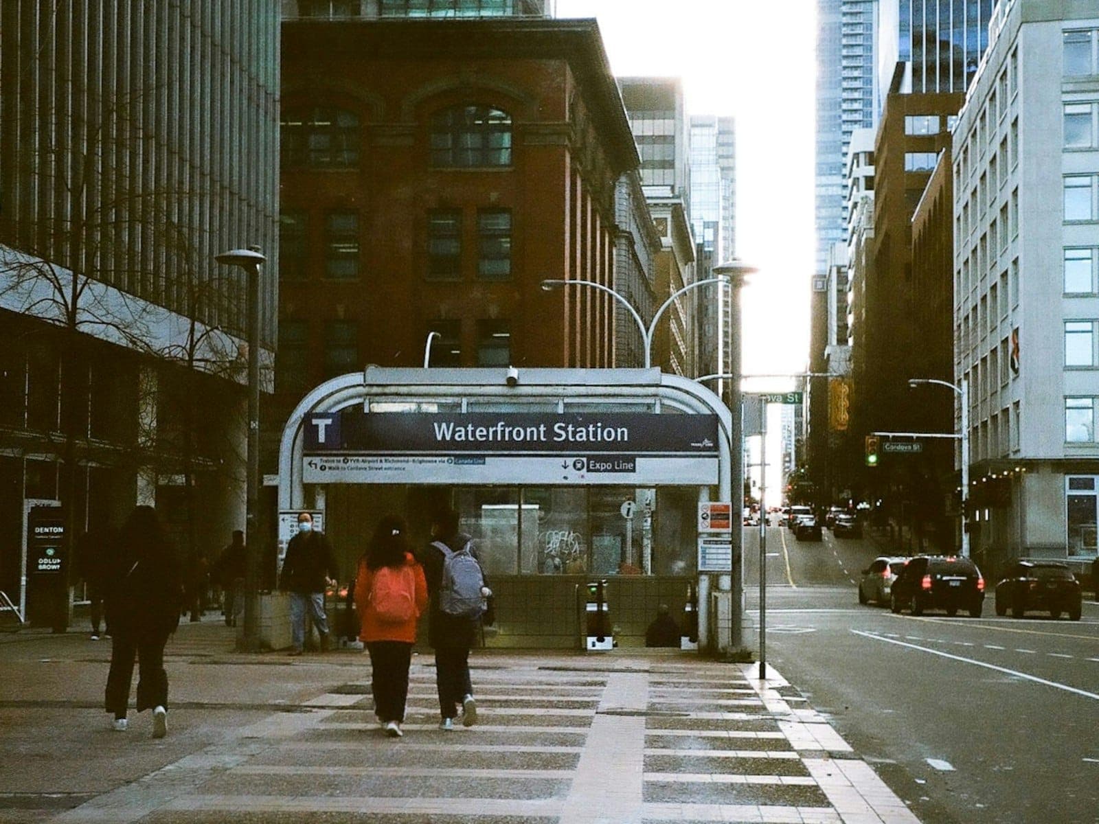 ผู้คนเดินผ่านทางเข้า Waterfront Station ในย่านดาวน์ทาวน์ของเมือง Vancouver ท่ามกลางอาคารในเมืองและความคึกคักบนท้องถนน