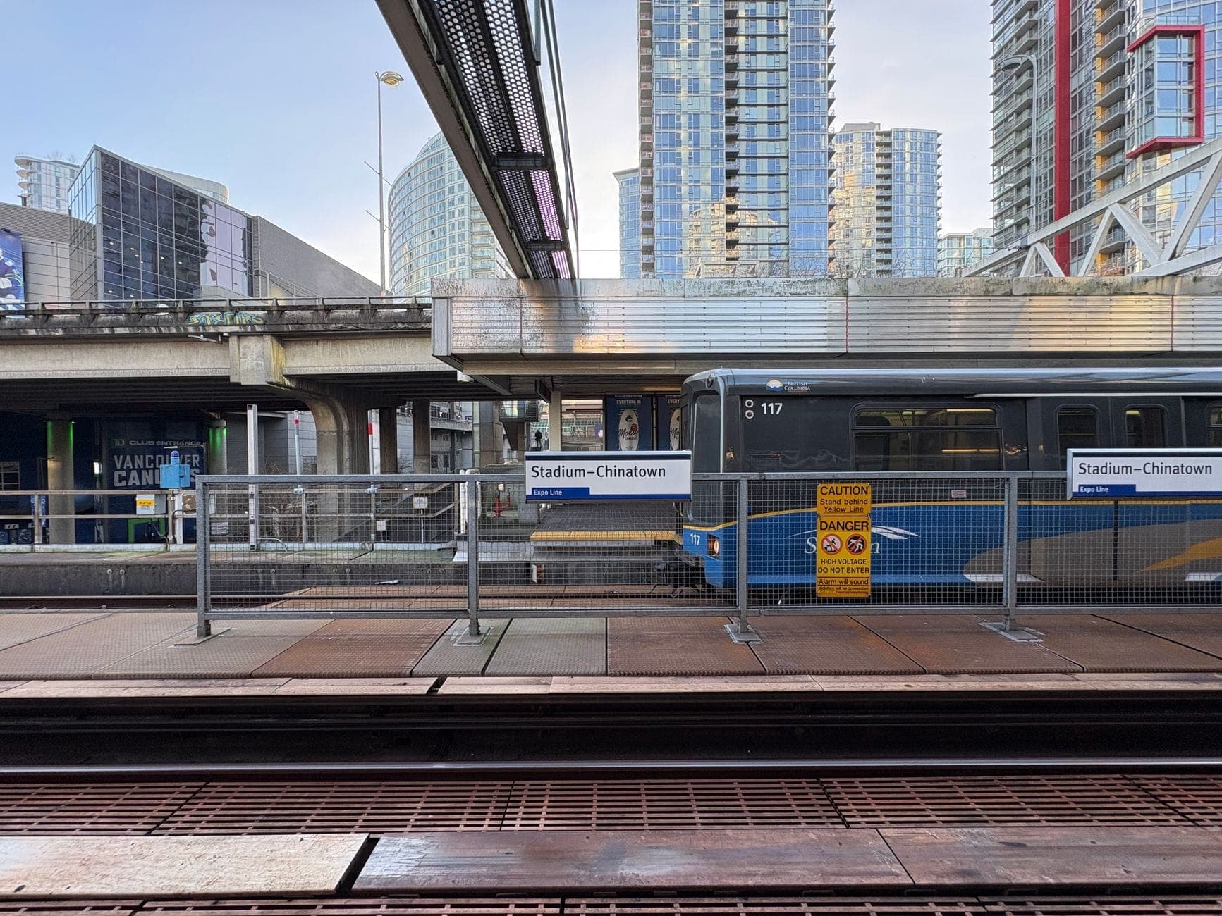 Vancouver SkyTrain ที่สถานี Stadium-Chinatown พร้อมรางรถไฟ ตู้รถไฟสีน้ำเงิน และตึกสูงใจกลางเมืองในพื้นหลัง