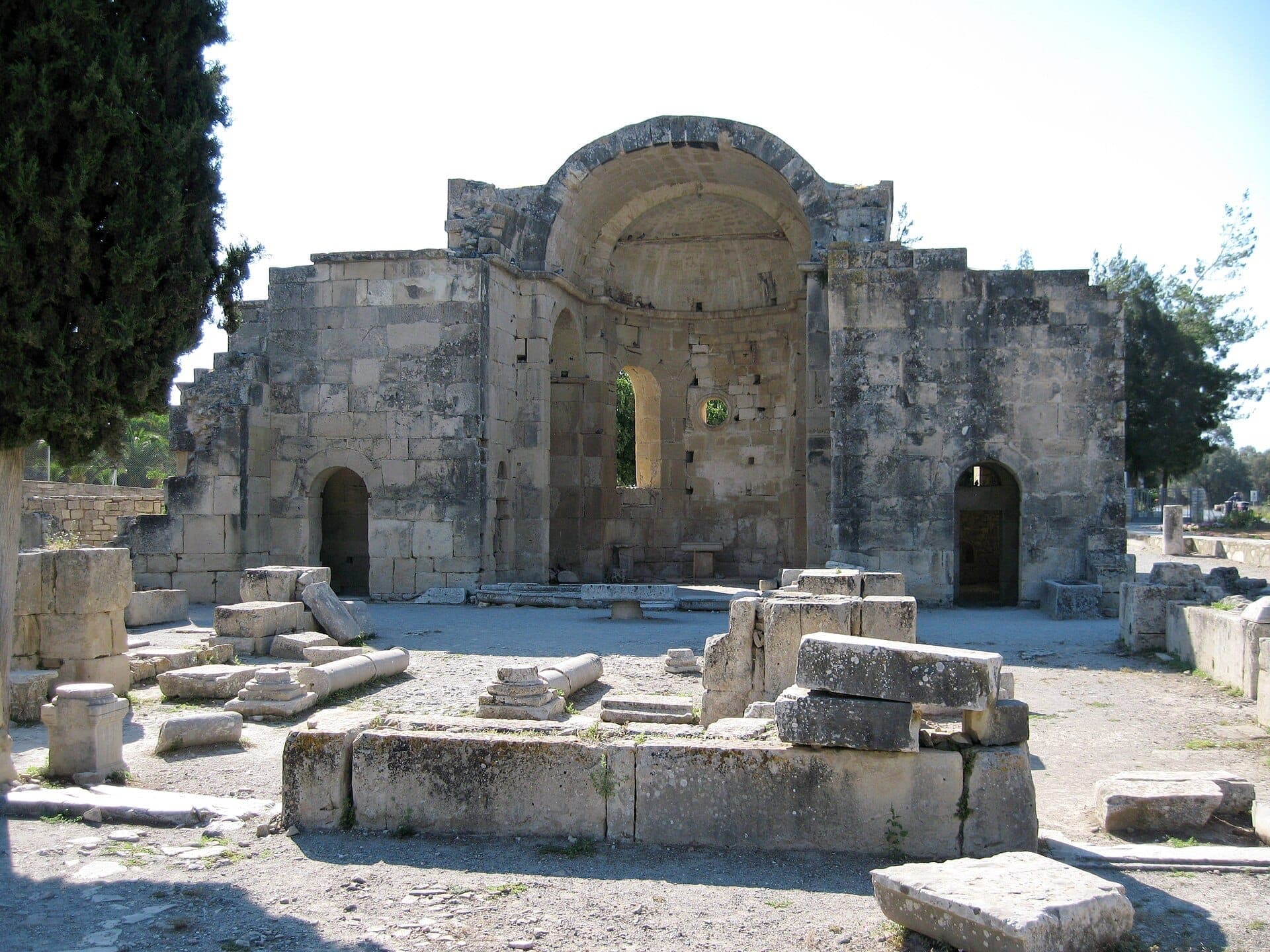 Ruinen der antiken Basilika von Gortyna auf Kreta, mit verwitterten Steinmauern, verstreuten Säulen und hellem Mittagssonnenlicht.