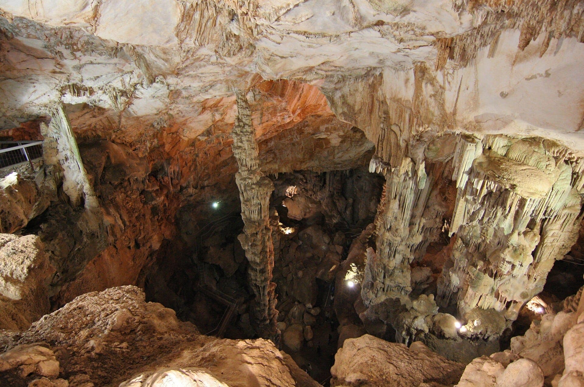Vista interior de las Grotte di Ispinigoli con la imponente estalagmita de caliza, formaciones rocosas dramáticas y paredes de la cueva iluminadas.