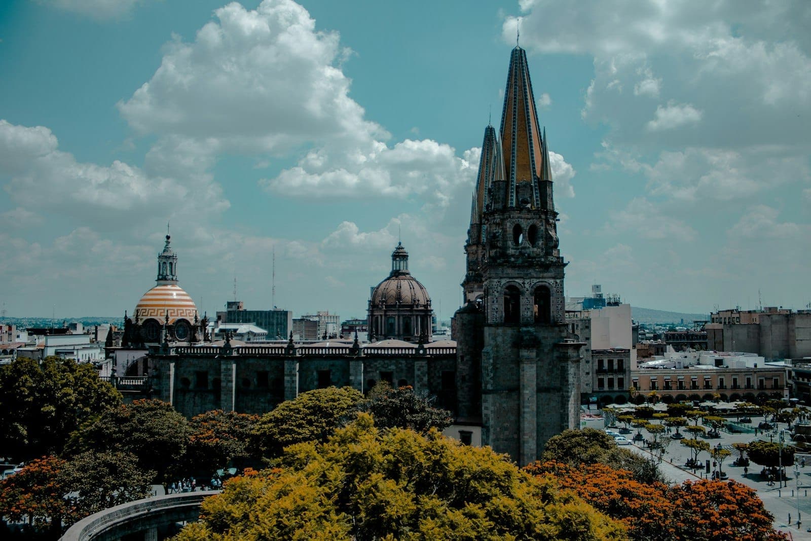 วิวกว้างของมหาวิหาร Guadalajara พร้อมหอคอยและโดมอันเป็นสัญลักษณ์ที่สูงเด่นเหนือต้นไม้โดยรอบและทิวทัศน์เมืองใต้ท้องฟ้าสีคราม